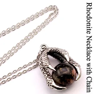 Detailed close-up of retro silver dragon claw pendant holding a marbled red stone bead