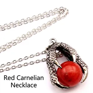 Close-up of a vintage medieval silver dragon claw pendant with a large red bead on a chain