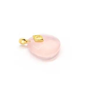 Macro detail of a faceted pink crystal pendant with a golden evil eye decorative charm
