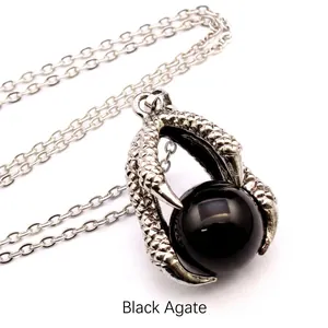 Close-up view of a medieval dragon claw pendant holding a polished black agate bead on a chain.