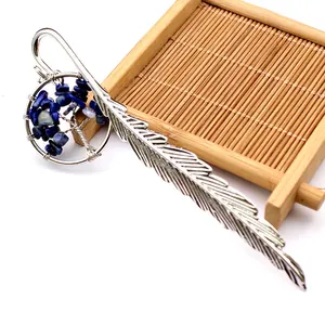 Detalle de primer plano de marcador de pluma plateada con dije de árbol de vida azul