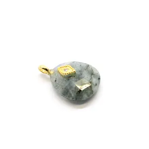 Detail of a teardrop amazonite pendant with gold evil eye charm and crystal.