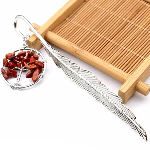 Detalle de marcapáginas de pluma plateada con colgante de árbol de la vida en piedras rojas