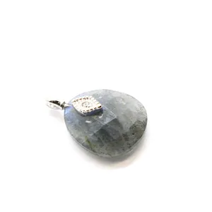 Detail shot of a faceted grey crystal pendant with a silver evil eye charm accent.