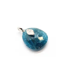 Close-up detail of blue Amazonite crystal pendant with silver evil eye charm and gold leaf.