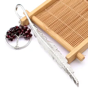 Primer plano de un marcador de libros de pluma de plata con colgante de cristal árbol de vida.