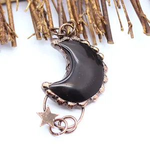 Primer plano de un colgante de luna vintage con obsidiana negra y estrella de bronce