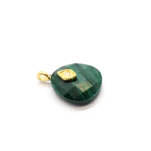 Close-up of a faceted green crystal pendant with a 24K gold-plated evil eye charm.