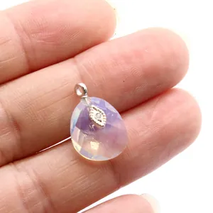 Close-up of small teardrop crystal pendant with eye detail held between fingers