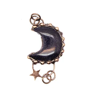 Primer plano detallado de un colgante de luna vintage en bronce con piedra azul arena