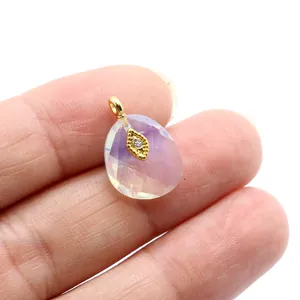 Macro close-up of faceted lavender crystal pendant with gold-plated evil eye detail