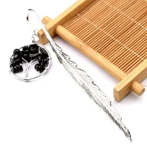 Detalle de marcapáginas de pluma plateada con colgante de árbol de vida en cristal negro