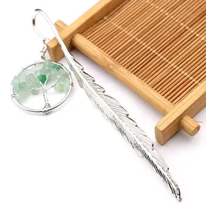 Detalle macro de un marcapáginas de pluma de plata con colgante árbol de la vida verde