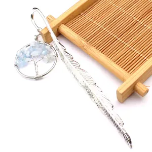 Detalle de marcapáginas de pluma plateada con colgante de árbol de la vida sobre bambú