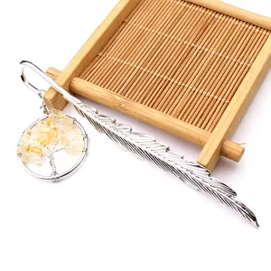 Primer plano de marcapáginas pluma de metal con colgante de árbol de la vida de cristal