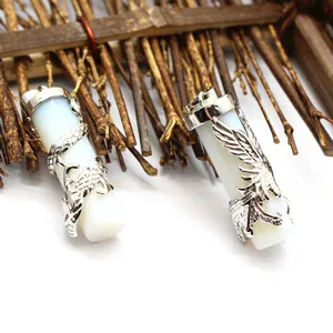 Close-up of intricate dragon and phoenix column pendants on a rustic wooden stick background.