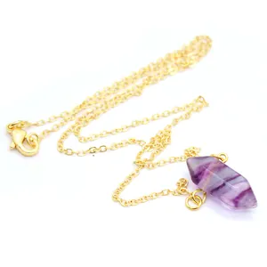 Detailopname van een paarse fluoriet kristallen hanger aan een gouden ketting.