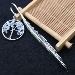 Detalle de marcapáginas de pluma plateada con colgante de árbol de vida de cristali