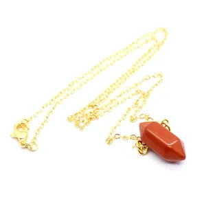 Close-up detail van een zeshoekige oranje kristallen hanger aan een gouden ketting