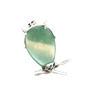 Primer plano de un colgante de búho con piedra verde y base de rama plateada.