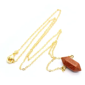 Detail van een zeshoekige goudsteen kristallen hanger aan een 24K vergulde ketting