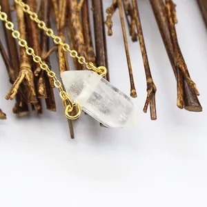 Macrodetail van een heldere zeshoekige kristallen hanger aan een 24K vergulde gouden ketting