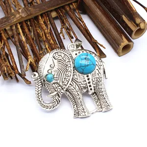 Gedetailleerd zicht op zilveren olifantenhanger met turquoise stenen op houten achtergrond