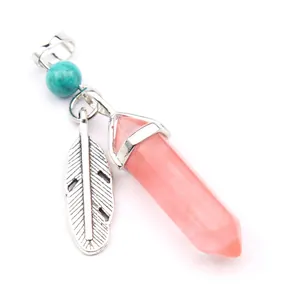 Macro view of pink crystal hexagonal pendant with silver feather charm and turquoise bead