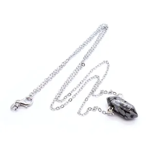 Detailopname van een zeshoekige gespikkelde kristallen hanger aan een zilverkleurige ketting