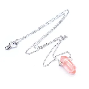 Close-up van een roze kristallen zeshoekige pilaar hanger ketting op wit.