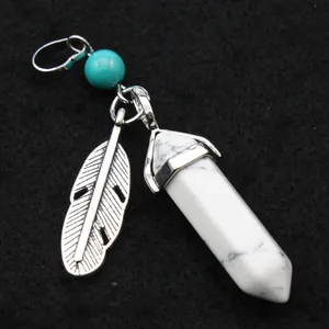 Macro detail of a white marble hexagonal crystal pendant with a silver feather charm