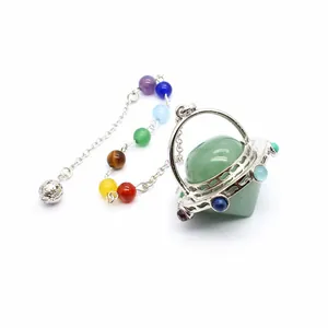 Detalle de un péndulo OVNI de cristal verde con una cadena de siete cuentas de chakra de colores