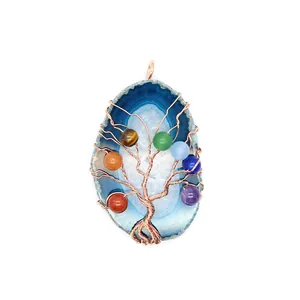 Detail van handgemaakte levensboom hanger met blauwe agaat schijf en koperdraad wikkeling