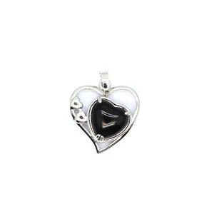 Détail d'un pendentif en forme de cœur argenté avec une pierre noire polie incrustée