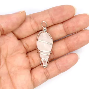 Detailed view of rose quartz hexagonal cone pendant with silver wire wrap held in palm