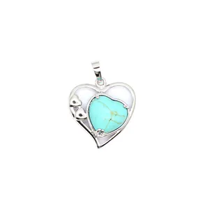 Détail d'un pendentif en forme de cœur argenté avec une pierre de turquoise incrustée