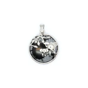 Vue détaillée du pendentif circulaire argenté orné d'un motif de maman et bébé éléphant