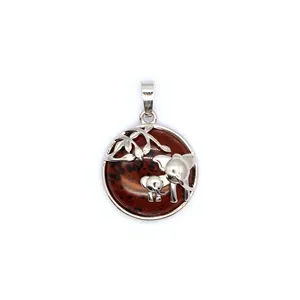 Gros plan d'un pendentif éléphant avec une pierre précieuse brun rouge sur blanc
