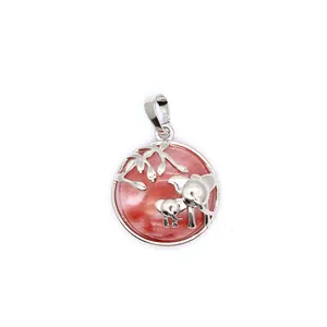 Gros plan d'un pendentif éléphant mère et enfant en argent avec pierre de sable rouge