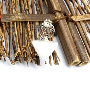 Detail shot of white crystal tree of life pendulum pendant with rustic wood background
