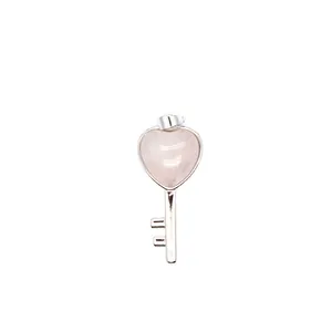 Detailed macro shot of a heart-shaped rose quartz crystal key pendant in a silver finish