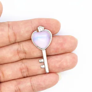 Detailed view of a silver heart-shaped key pendant with purple stone held in hand