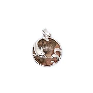 Macro detail of silver dolphin pendant featuring natural red aventurine gemstone