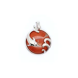 Macro detail view of a red aventurine dolphin pendant with a silver-toned wave design.