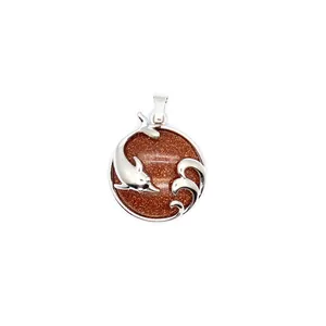 Detail view of a silver dolphin and wave pendant with a sparkling brown gemstone