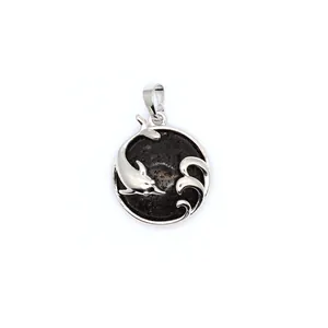 Macro view of silver dolphin pendant with black stone inlay and wave details