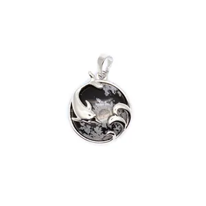 Detailed view of a polished silver dolphin and wave pendant with snowflake stone