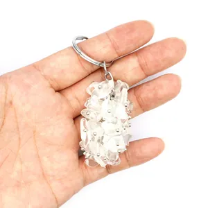 Detailed macro view of a clear quartz crystal chip keychain bag charm held in hand