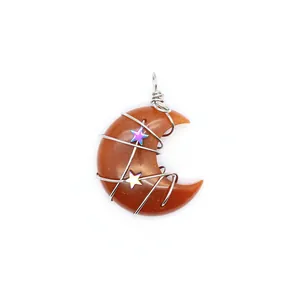 Detalle de un colgante de media luna de aventurina roja envuelto en alambre con dijes de estrellas.