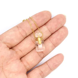 Vue détaillée d'un collier pendentif bouteille de parfum en cristal tenu en main.